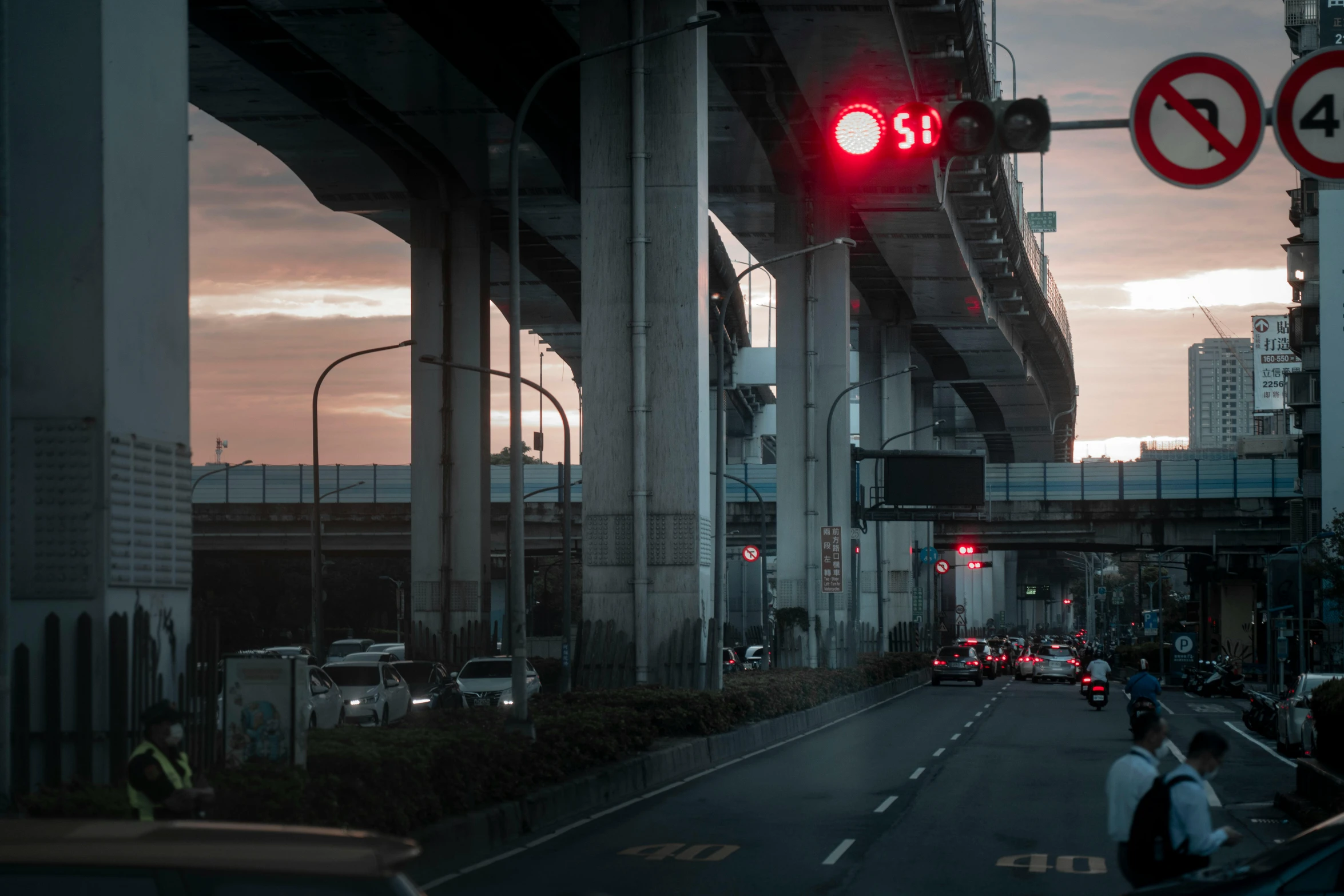 the sun is setting as traffic passes through a bridge