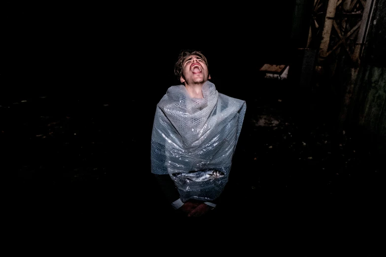 a man standing in the dark with a plastic jacket on his head