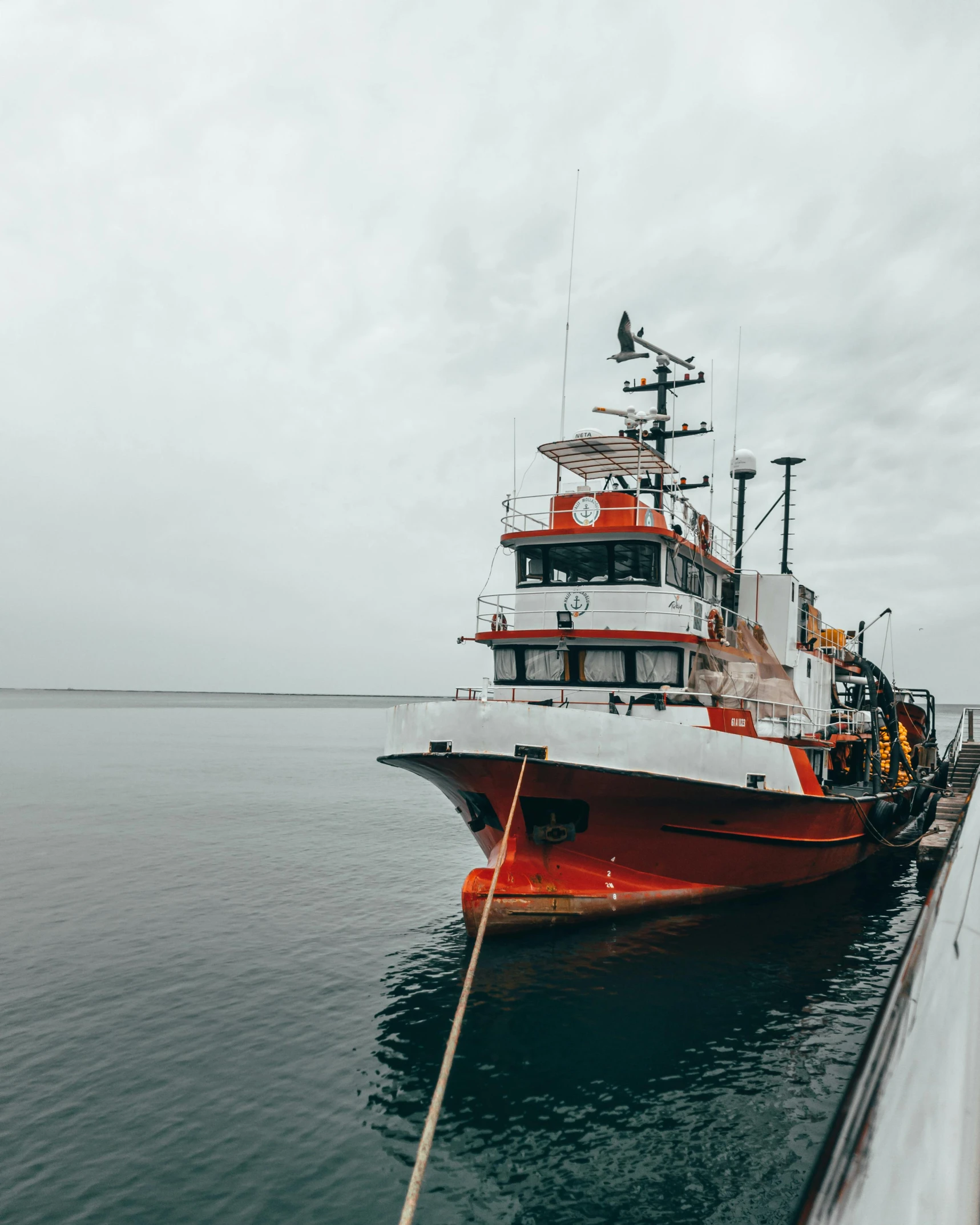 red and white boat with two people standing on deck looking at water