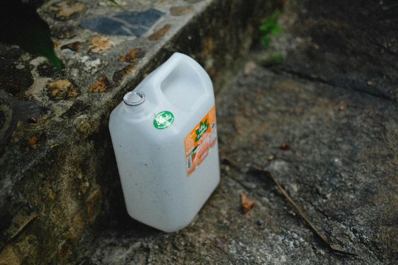 a plastic jug sitting next to a concrete wall