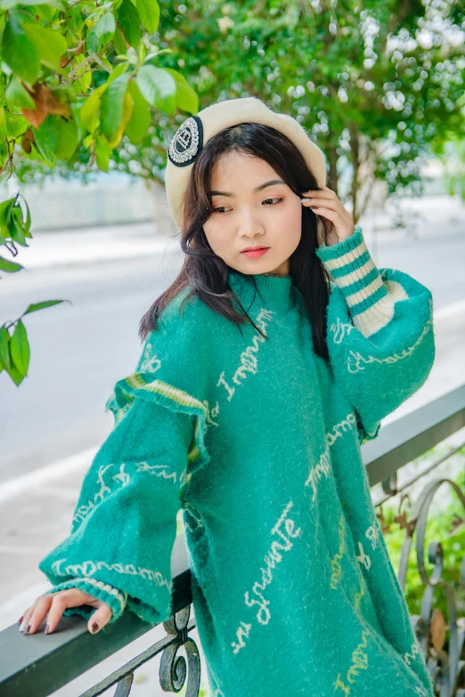 the young asian woman wearing green is leaning on the railing