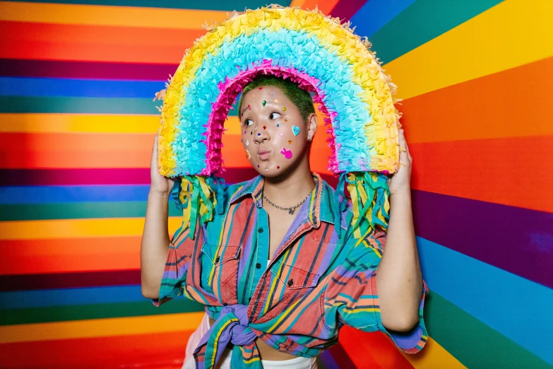 a person in rainbow colored outfits holds a pinata