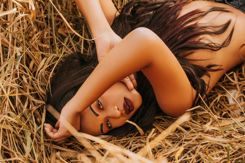 a woman lying down on top of a hay field