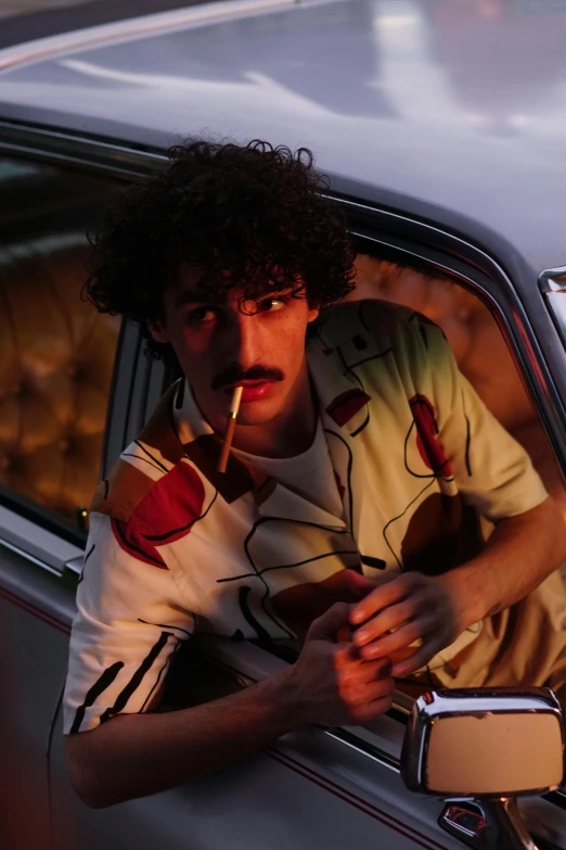 a man smoking in a car with an apple on his shirt