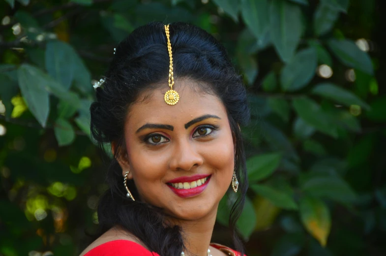 a woman wearing a necklace and ear ring smiles at the camera