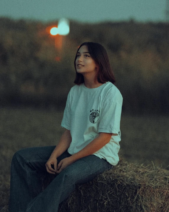 a girl sitting on hay with her hands in the air