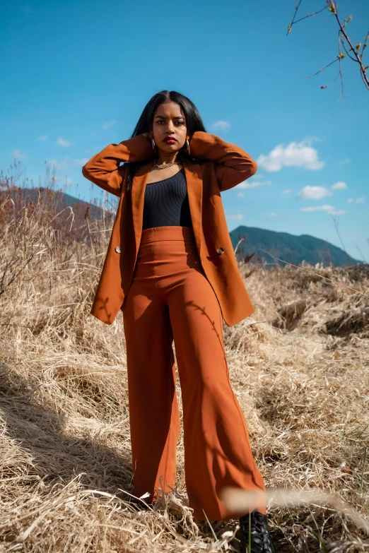 a woman poses in a field of dry grass