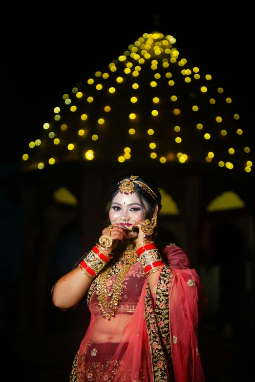 a bride in traditional indian garb stands next to her bridal dress