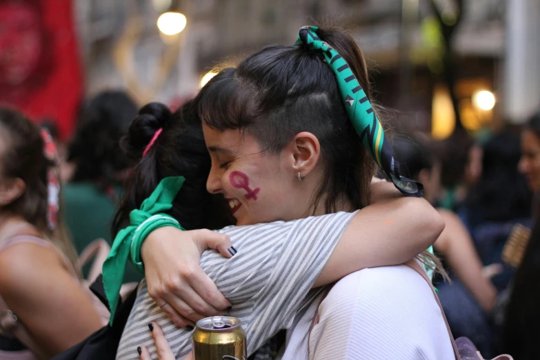 two people hugging in the crowd with clown nose painted on them