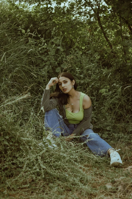 a woman sitting in a field holding a cigarette