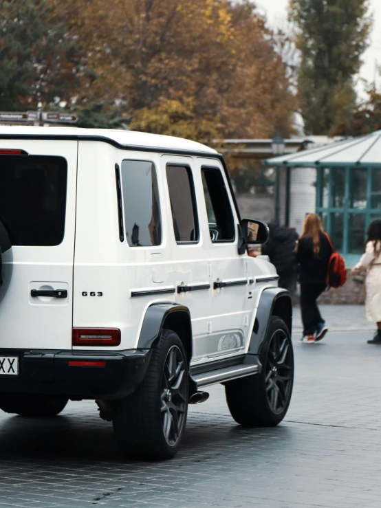 a white vehicle on the road with people in the background