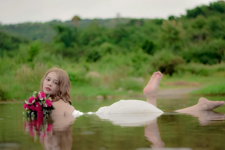 a woman in a white dress lying on the water