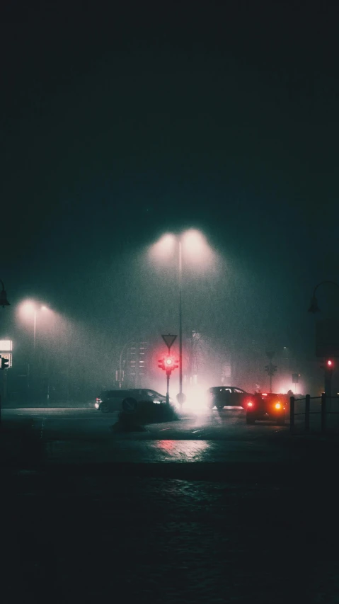 two traffic lights with a car on the street at night