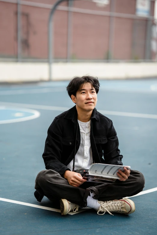 a man sitting on the basketball court with a book