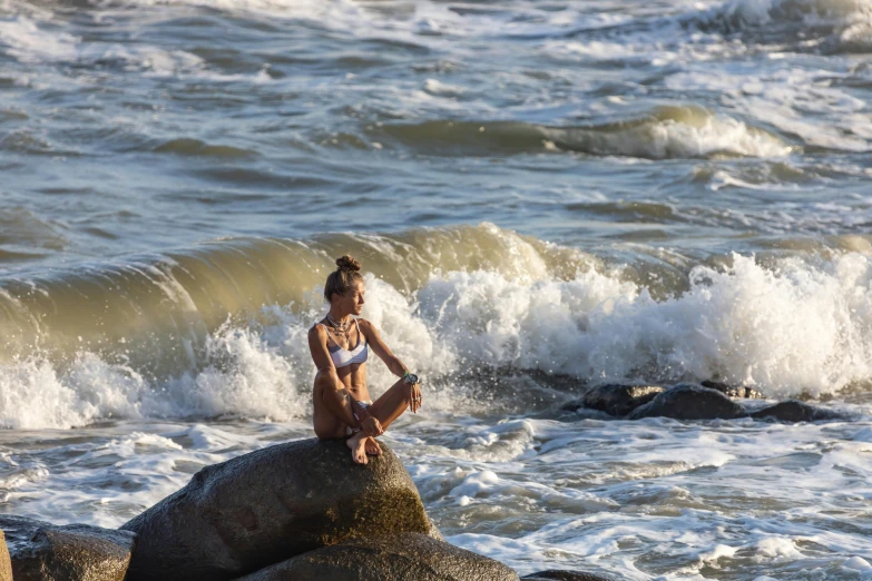 a woman sitting on a rock with her legs crossed