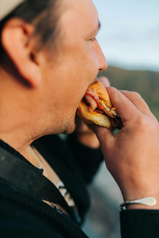 a man is taking a bite out of a sausage sandwich