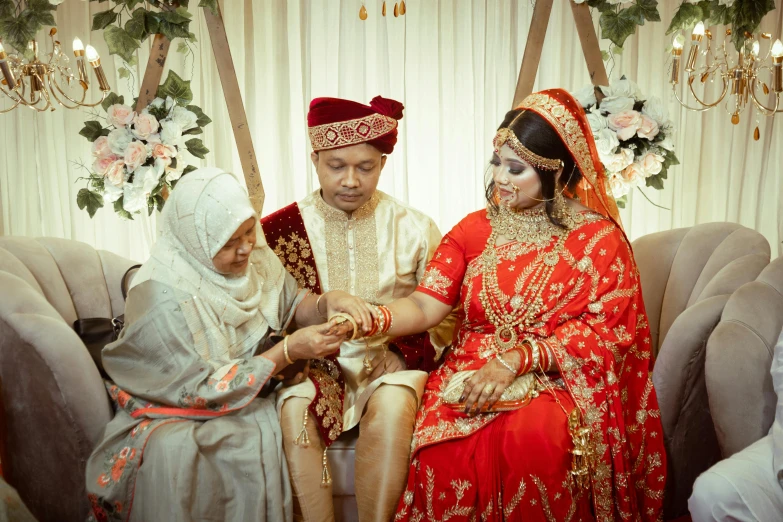 two people wearing wedding clothes sitting in a chair