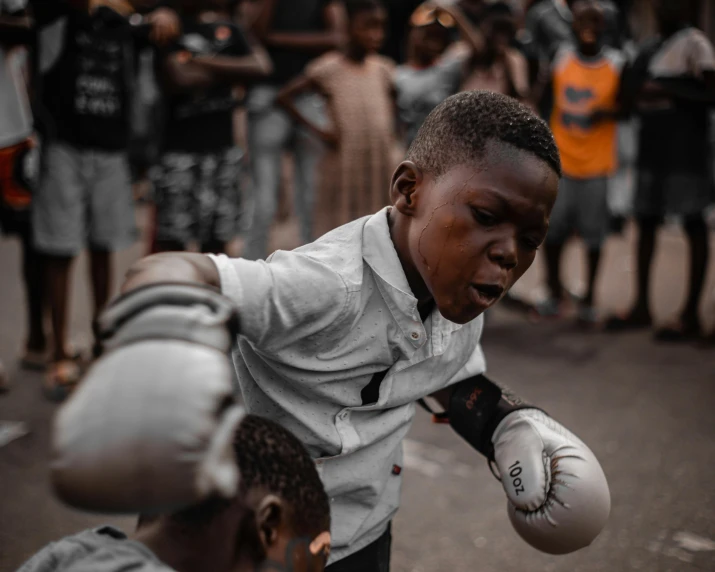 a boy on street boxing with white gloves on