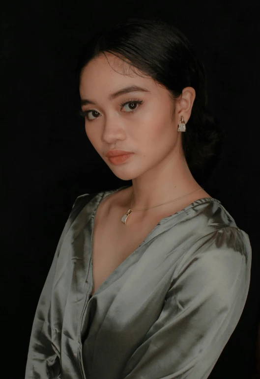 a woman wearing a dress and earrings poses for the camera