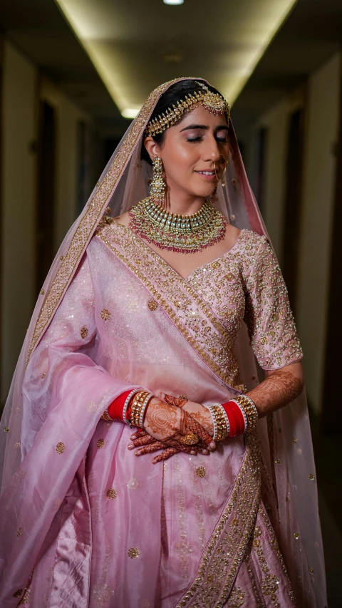 an indian woman dressed in a pink bridal gown