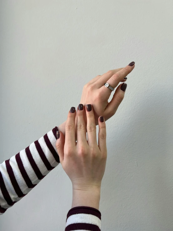 two hands holding onto a nail brush and one holding another