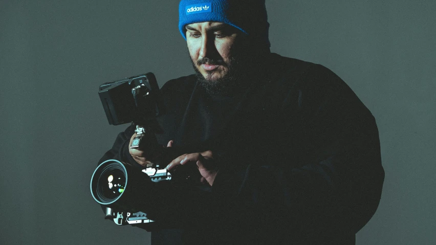 a man holding a camera wearing a blue cap