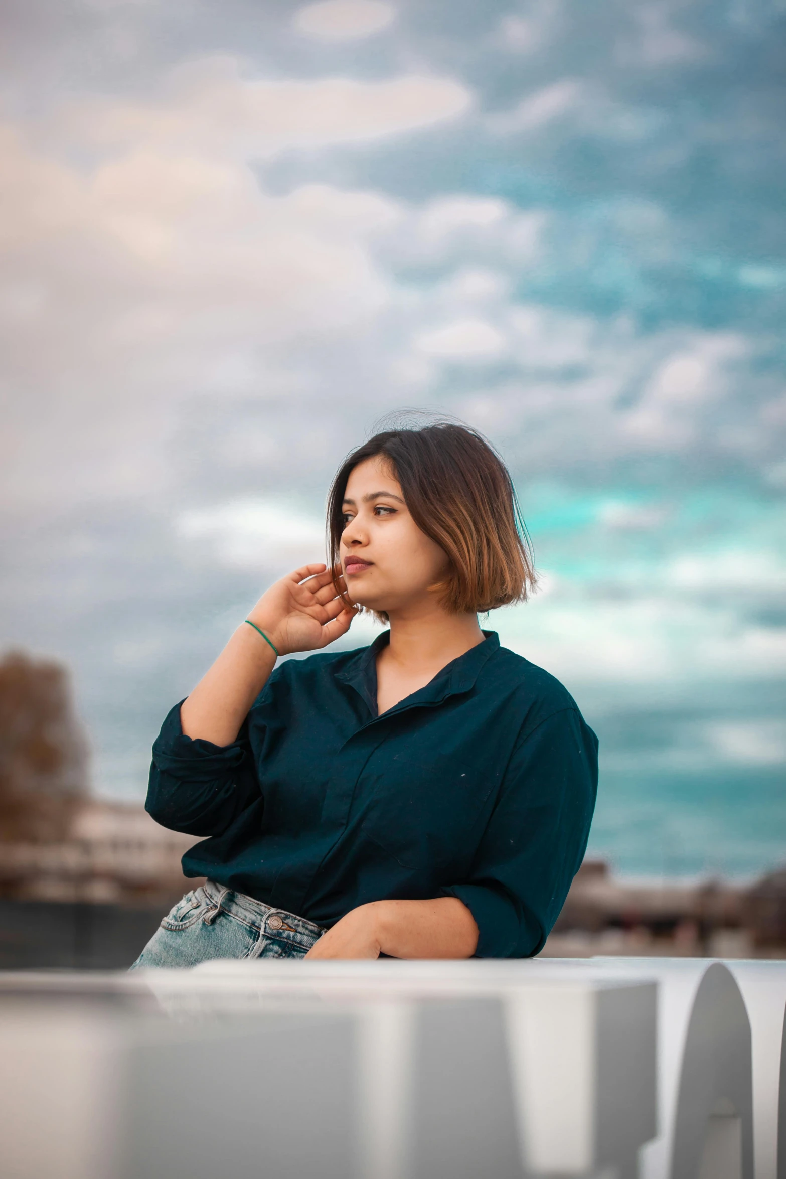 a woman sitting down next to a railing on a cloudy day