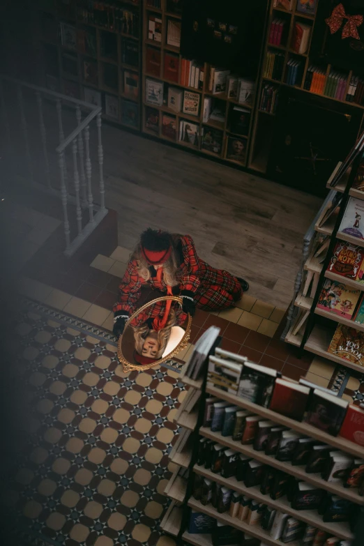 man sitting on the ground in front of bookshelves