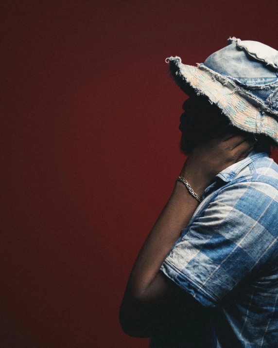 a woman wearing a straw hat in front of red wall