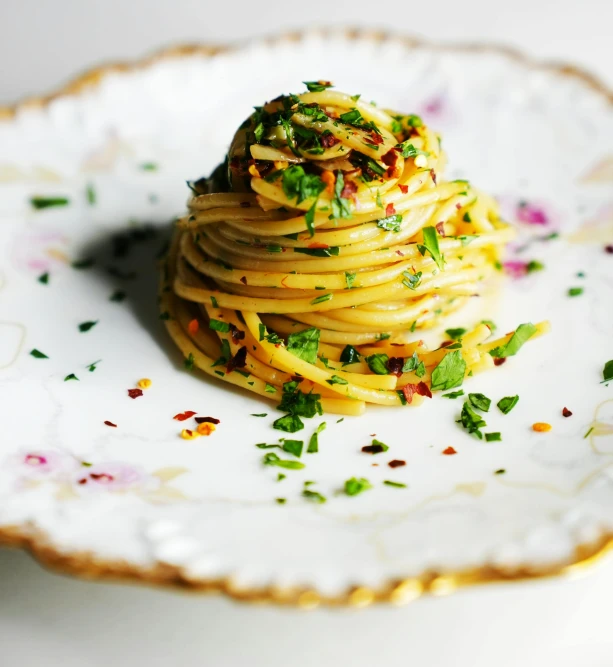 there is pasta on a white plate with flowers and herbs