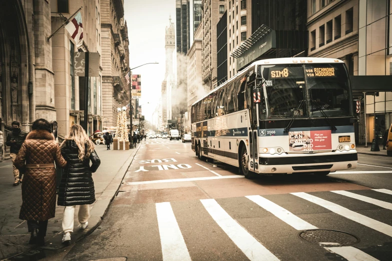 bus on street with pedestrians on sidewalk near buildings