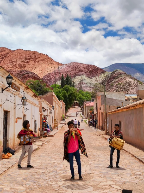 some people walking in an alley with mountains in the background