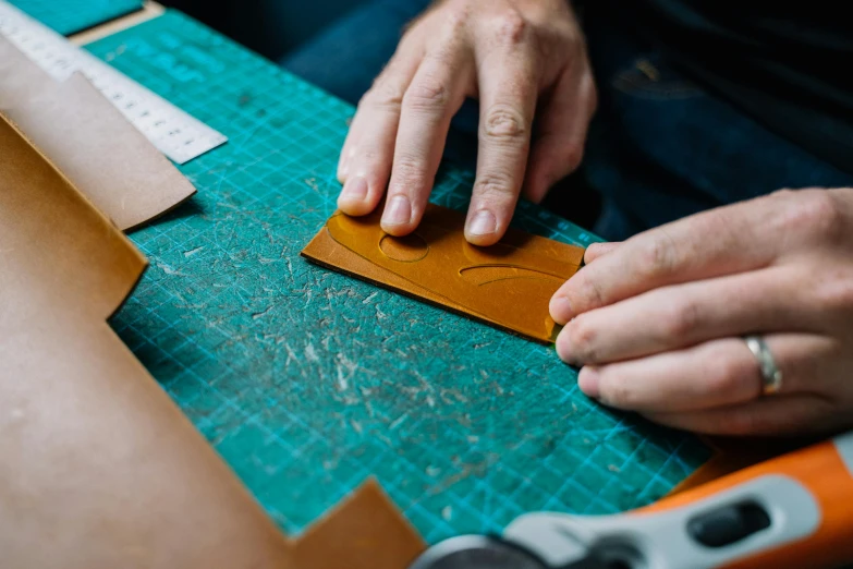 someone using a cutter to cut leather on a piece of fabric