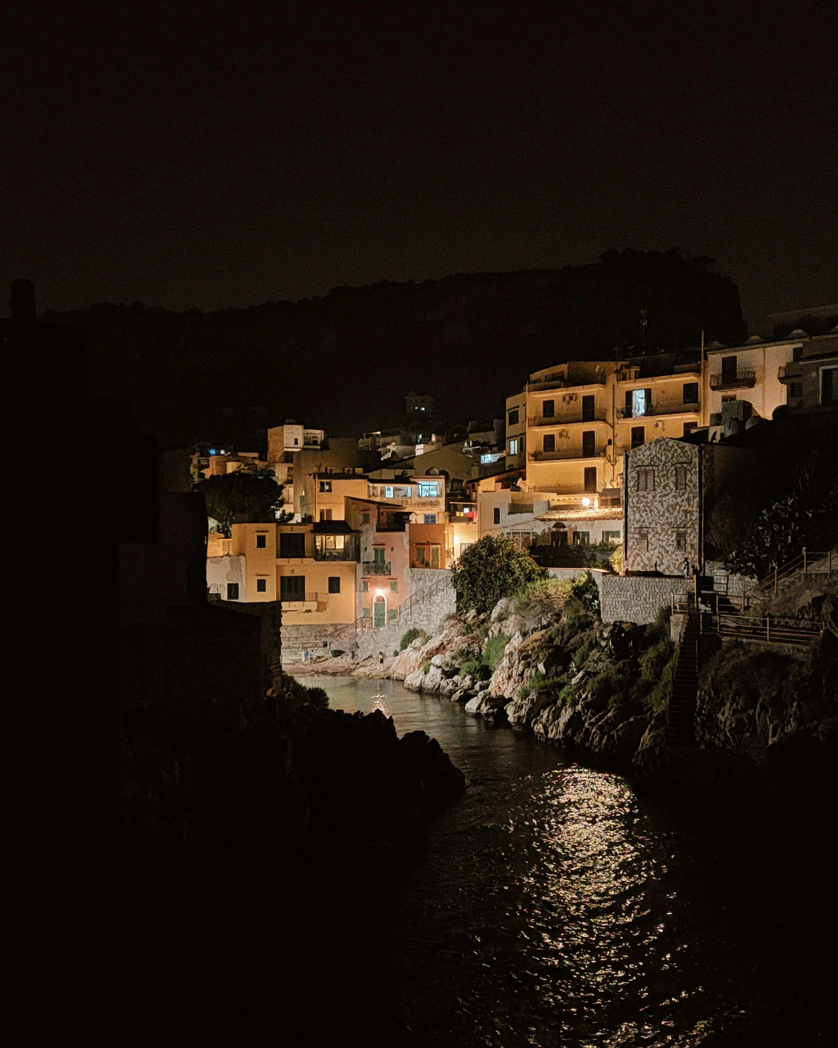 a nighttime view of an urban river that is lit by the lights of a city