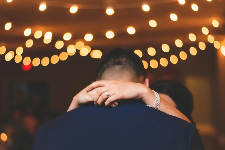 a bride holds the groom's arm as he sees them dance