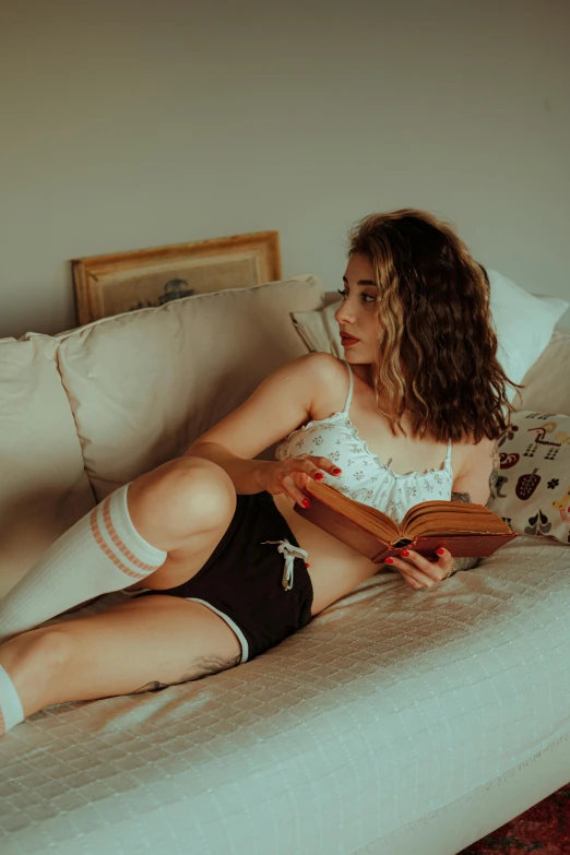 a girl laying down on a bed reading a book