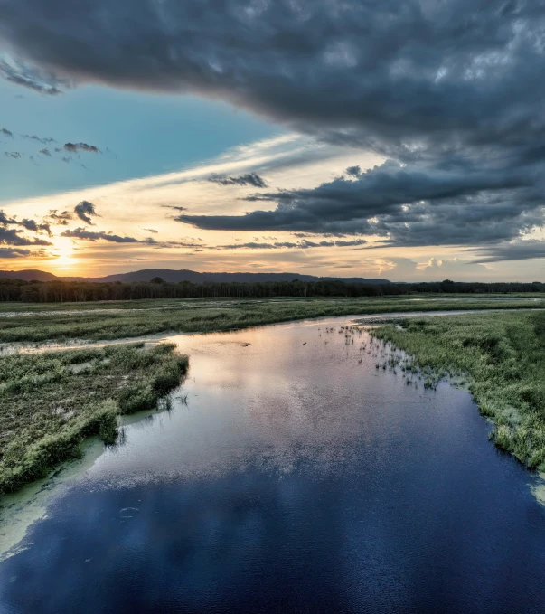 an image of sunset over a river and land