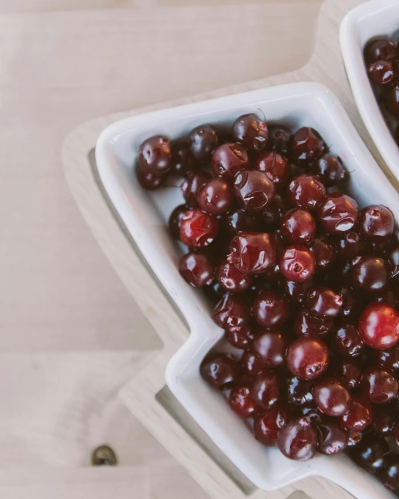 a bowl of cherries on a table with a cloth