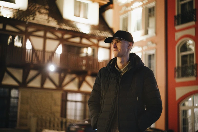 the man stands in front of a building that is lit by streetlights