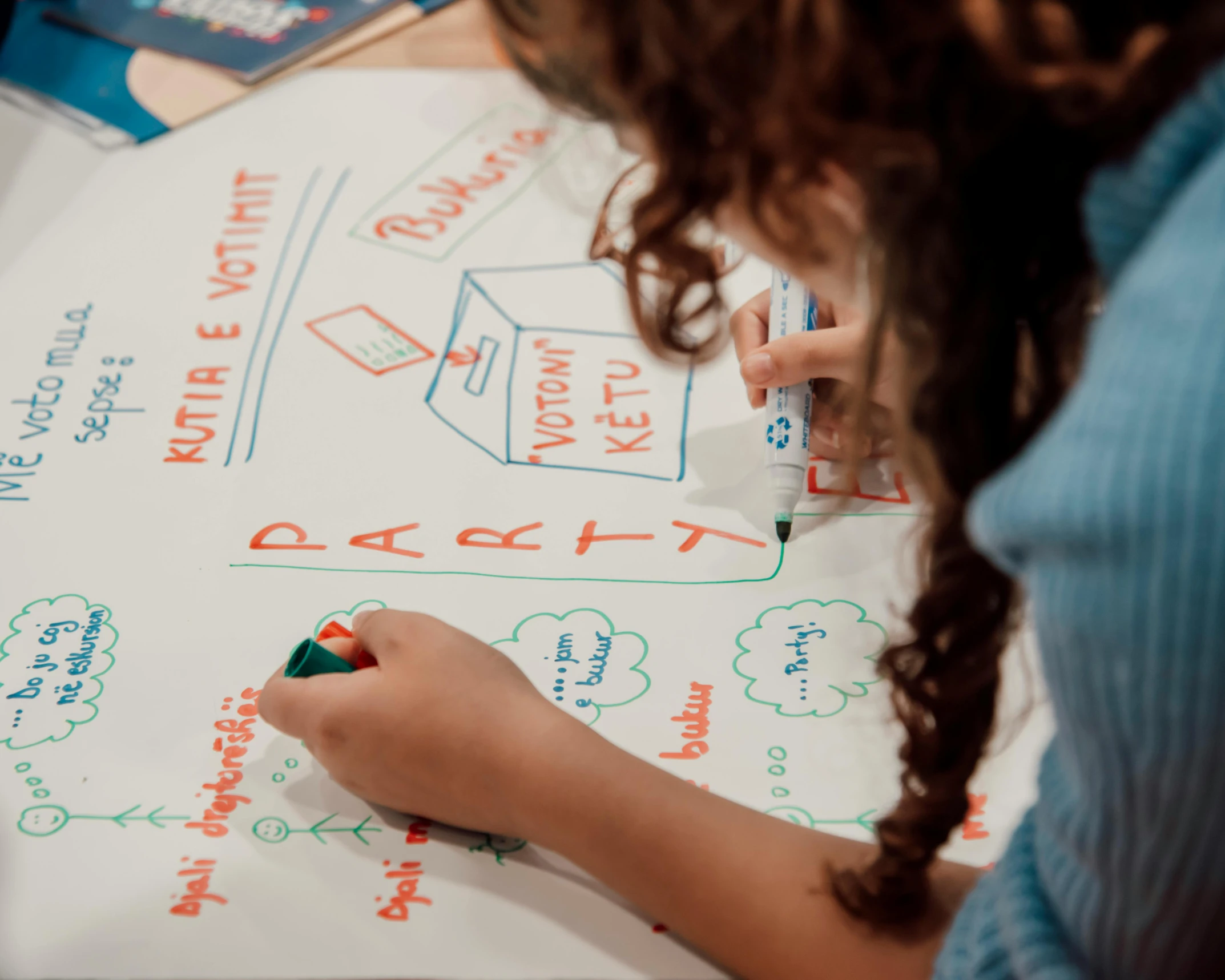 girl on top of a large white board drawing on the ground