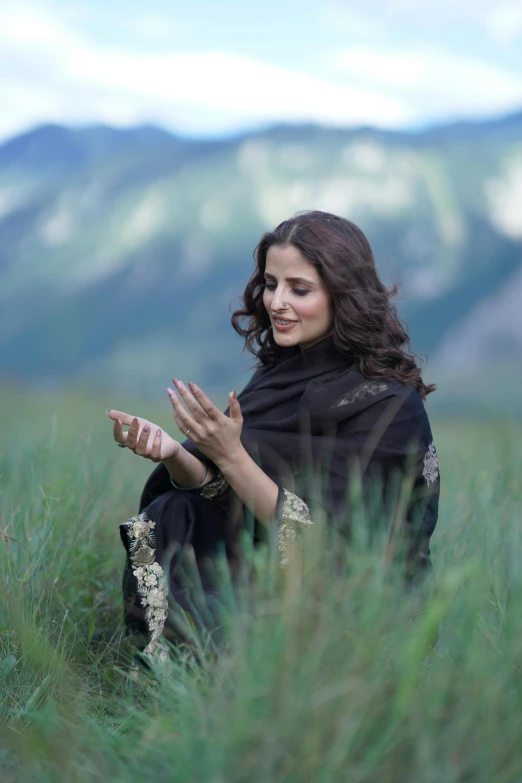 a woman wearing a black outfit is sitting in a green field