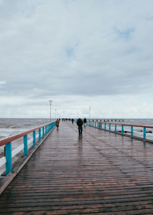 a walkway in front of the ocean with people walking along the end