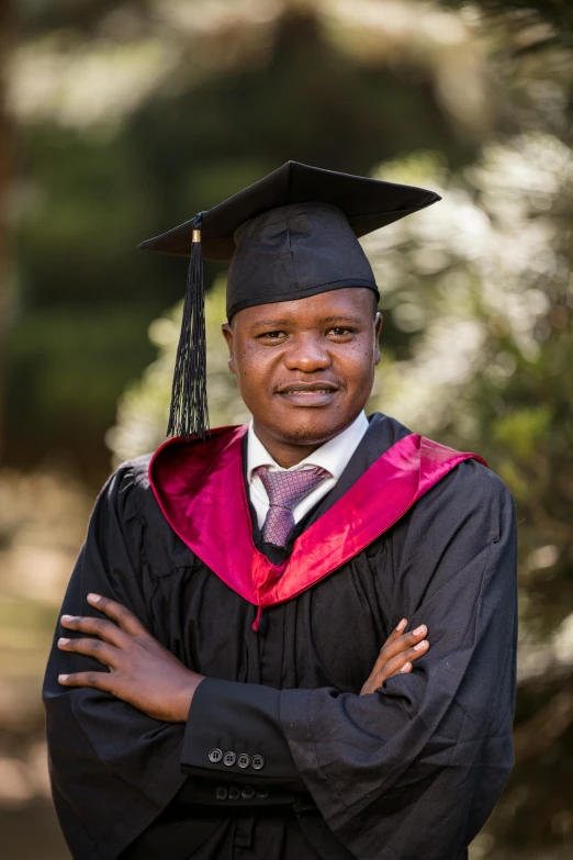 a man with his arms crossed and graduation cap on