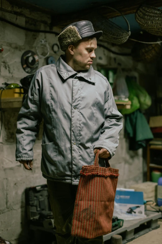 a man standing with a red bag and a hat