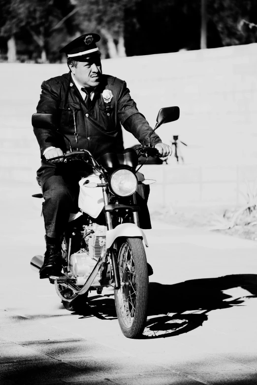 a man riding a motorcycle down a street in black and white