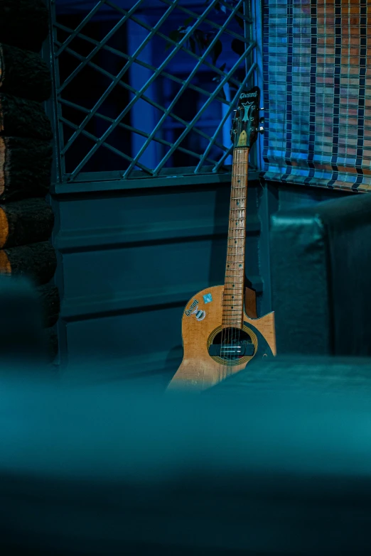 a guitar sitting on the ground in front of a metal grill