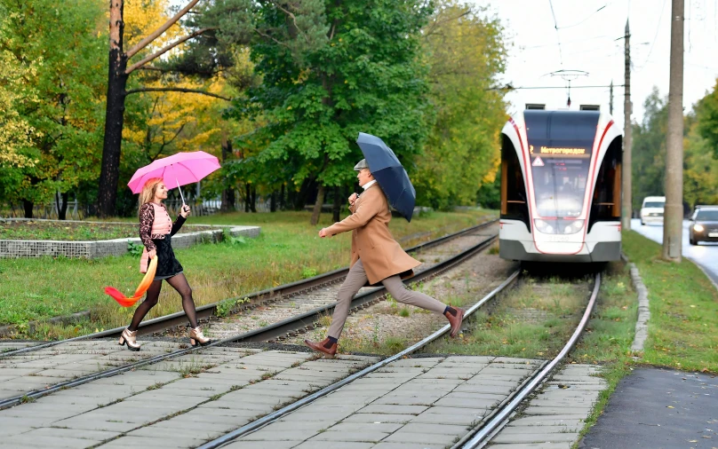 two people walk on a track, one has an umbrella