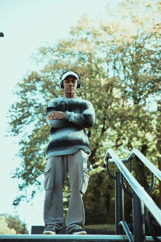 the man is posing with his arms crossed near some stairs