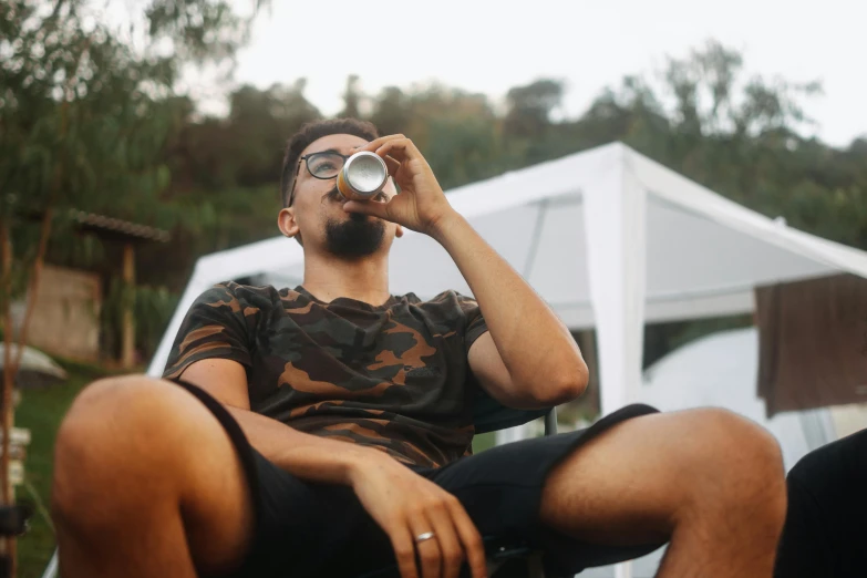 a man sitting in a chair drinking from his beer glass