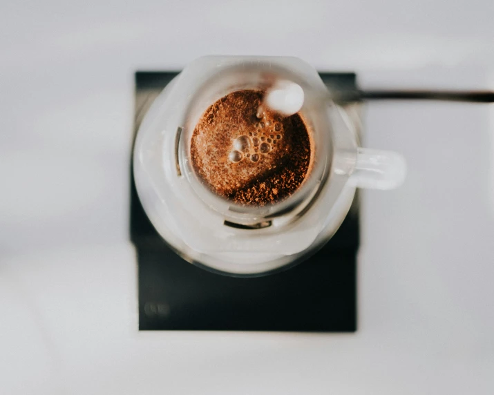 a cup filled with brown liquid sitting on top of a black coaster